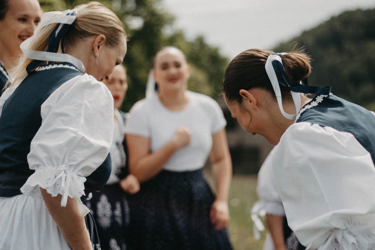 Speváčky folklórnej skupiny Kopanice v krojoch sa smejú na lúke