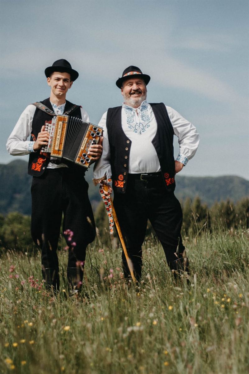 Heligonkár a starejší FS Kopanice v krojoch s valaškou na lúke