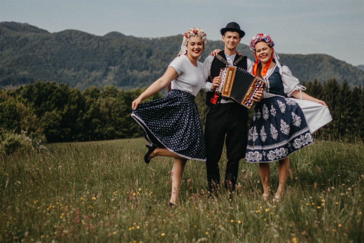 Dve tanečnice s harmonikárom v krojoch na lúke
